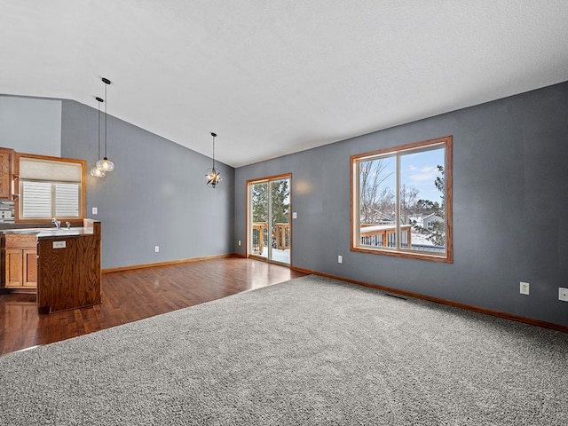 unfurnished living room featuring baseboards, visible vents, dark wood-style flooring, vaulted ceiling, and dark carpet