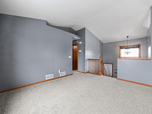 spare room with carpet floors, lofted ceiling, visible vents, and baseboards