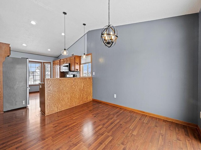 kitchen with vaulted ceiling, a peninsula, appliances with stainless steel finishes, and dark wood-style flooring