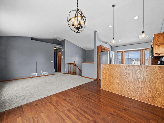 interior space featuring dark wood-style flooring, pendant lighting, brown cabinetry, vaulted ceiling, and baseboards