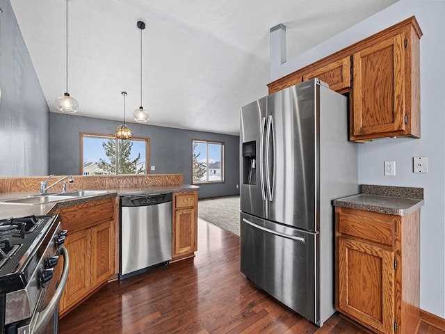 kitchen featuring brown cabinetry, pendant lighting, stainless steel appliances, and a sink