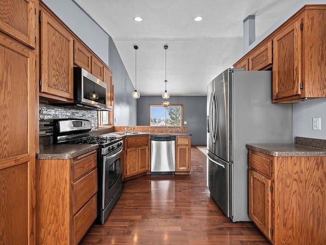 kitchen featuring a peninsula, brown cabinetry, and stainless steel appliances