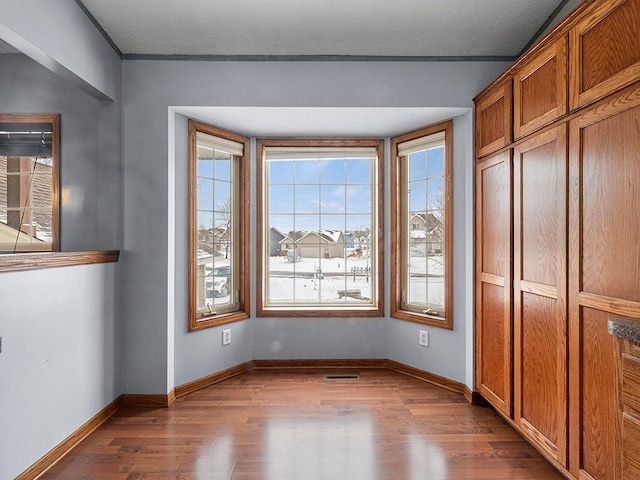 unfurnished dining area featuring wood finished floors, visible vents, and baseboards