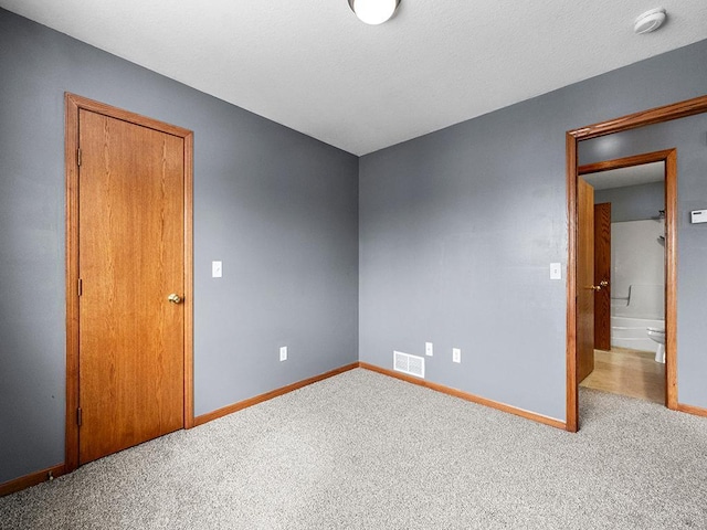 carpeted spare room with visible vents, baseboards, and a textured ceiling