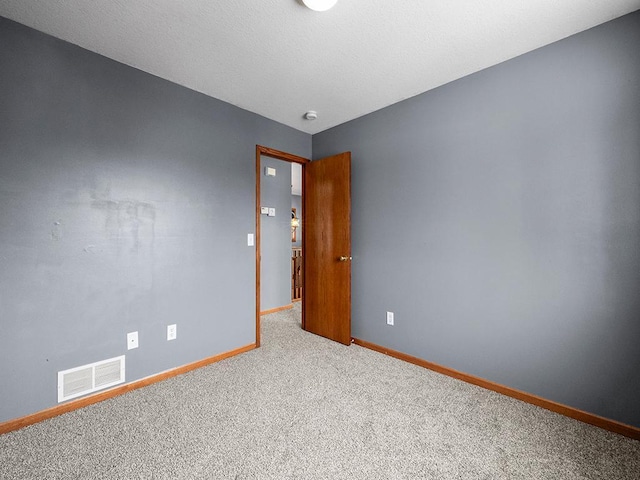 unfurnished room featuring carpet floors, visible vents, a textured ceiling, and baseboards