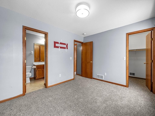 unfurnished bedroom with carpet, a spacious closet, visible vents, and baseboards