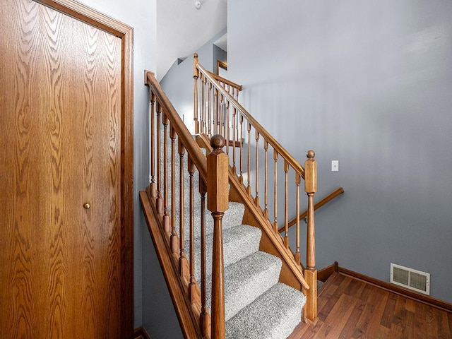 stairway with wood finished floors, visible vents, and baseboards