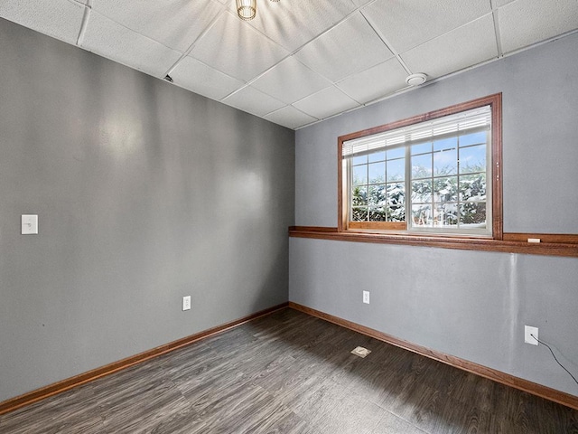 unfurnished room featuring a paneled ceiling, baseboards, and wood finished floors