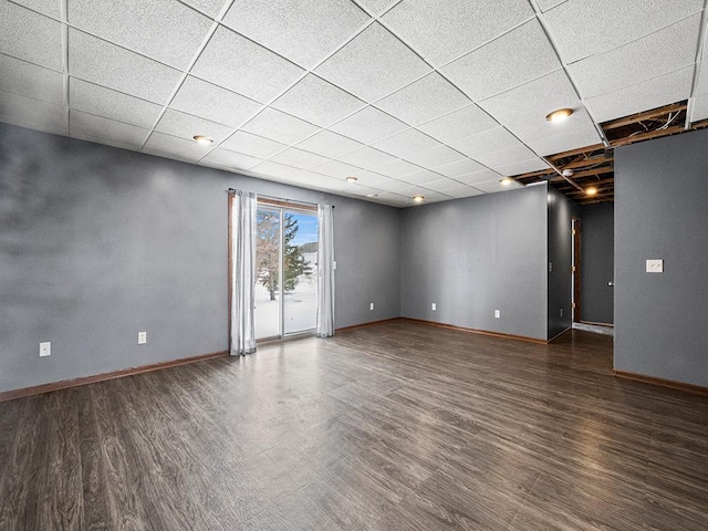 spare room featuring wood finished floors, a paneled ceiling, and baseboards