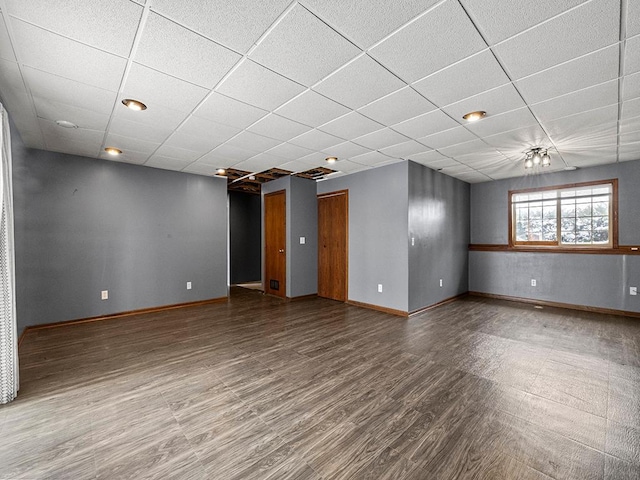 unfurnished room with baseboards, a drop ceiling, and wood finished floors