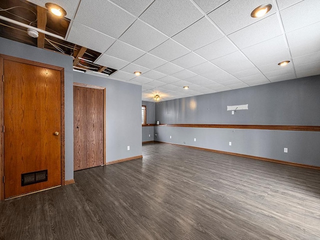 interior space with a paneled ceiling, wood finished floors, visible vents, and baseboards