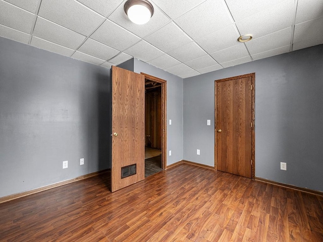 unfurnished bedroom with visible vents, wood finished floors, a paneled ceiling, and baseboards