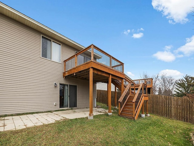 rear view of property with a deck, fence, stairway, a lawn, and a patio area