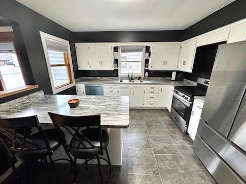 kitchen featuring white cabinets, appliances with stainless steel finishes, sink, and a breakfast bar