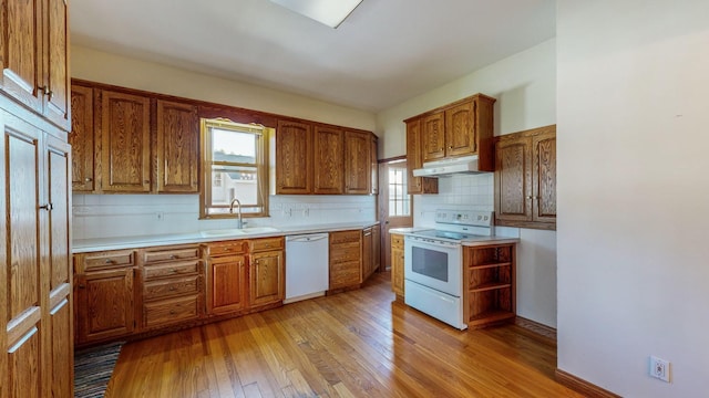 kitchen with light hardwood / wood-style floors, tasteful backsplash, sink, and white appliances