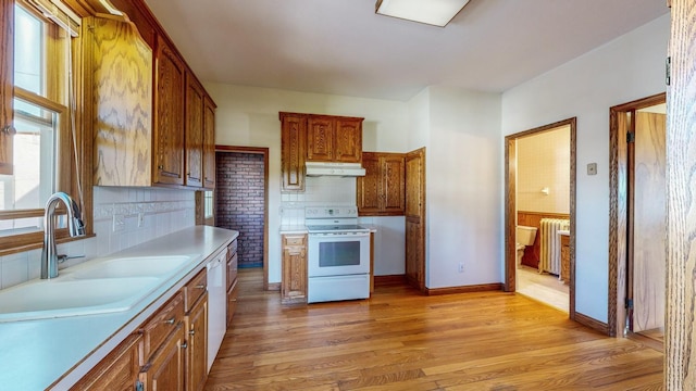 kitchen with radiator heating unit, white appliances, sink, and light hardwood / wood-style floors