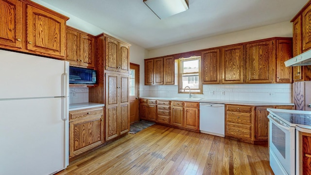 kitchen featuring extractor fan, sink, decorative backsplash, white appliances, and light hardwood / wood-style flooring