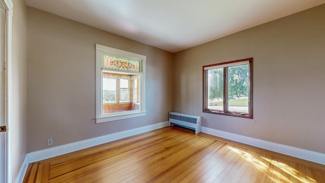 empty room featuring radiator heating unit and light wood-type flooring