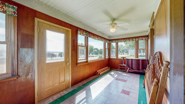 sunroom / solarium featuring a baseboard heating unit and ceiling fan