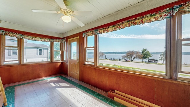 unfurnished sunroom with a water view and ceiling fan