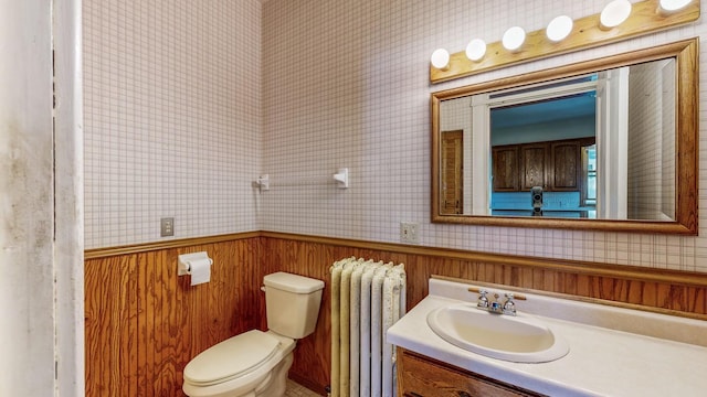 bathroom with toilet, wood walls, radiator heating unit, and vanity