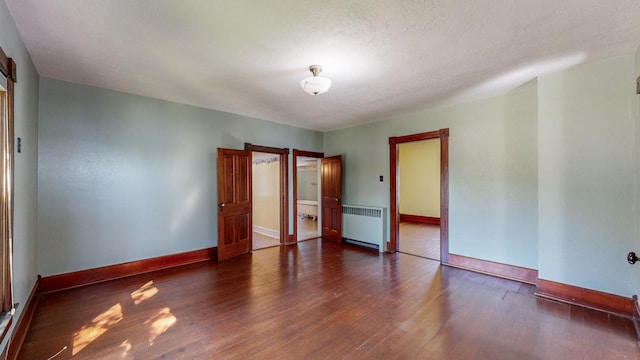 unfurnished bedroom with radiator, a textured ceiling, and dark hardwood / wood-style floors