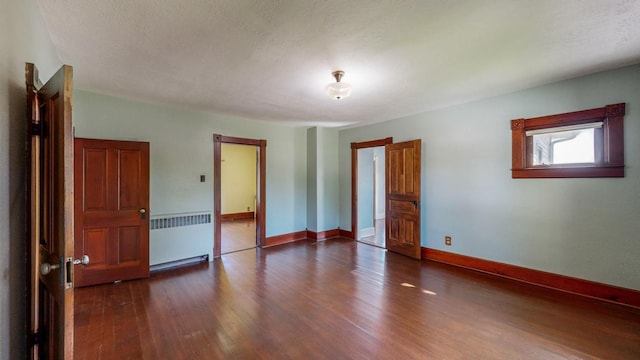 interior space with a textured ceiling, dark hardwood / wood-style floors, and radiator