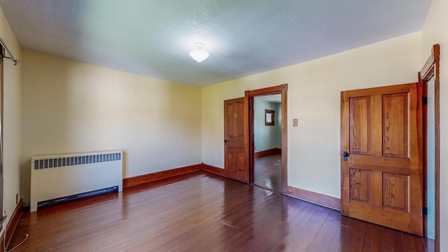 unfurnished bedroom featuring dark wood-type flooring and radiator