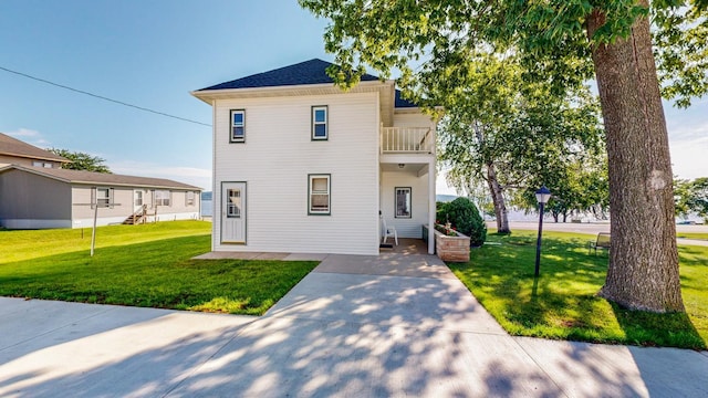 view of front of house with a front yard and a balcony