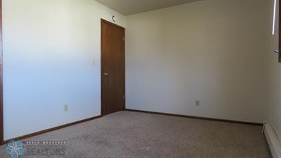 spare room with a baseboard heating unit and light colored carpet