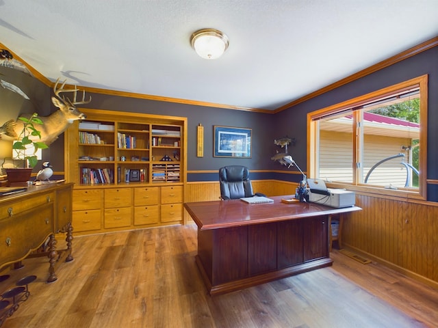 home office featuring hardwood / wood-style floors, wooden walls, a textured ceiling, and ornamental molding