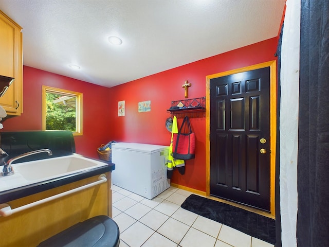 laundry room featuring cabinets, a textured ceiling, light tile patterned floors, and sink