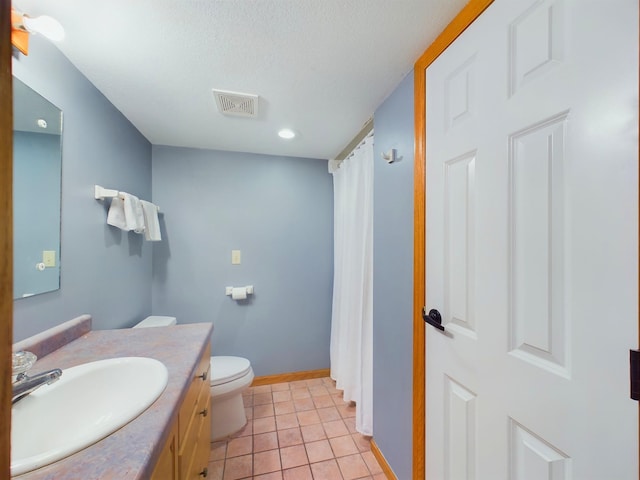 bathroom featuring toilet, vanity, a textured ceiling, and tile patterned flooring