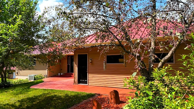 back of house with central air condition unit, a yard, and a patio area