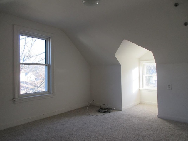 additional living space featuring lofted ceiling, light colored carpet, and plenty of natural light