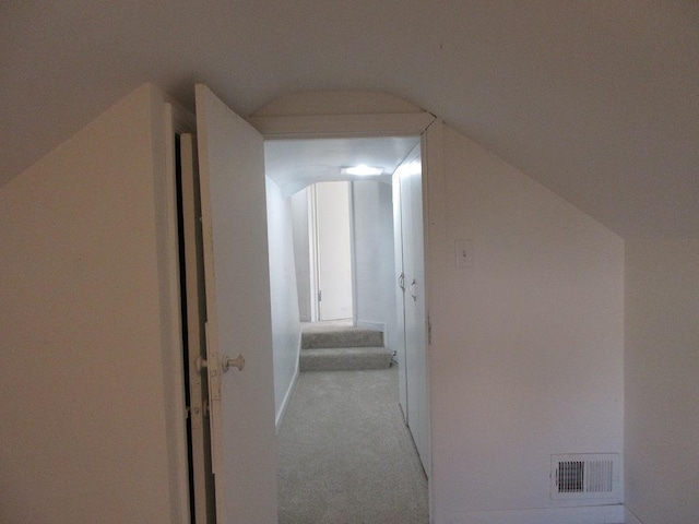 hallway with vaulted ceiling and light colored carpet