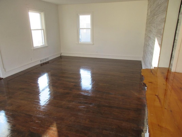 unfurnished room featuring a healthy amount of sunlight and dark hardwood / wood-style flooring