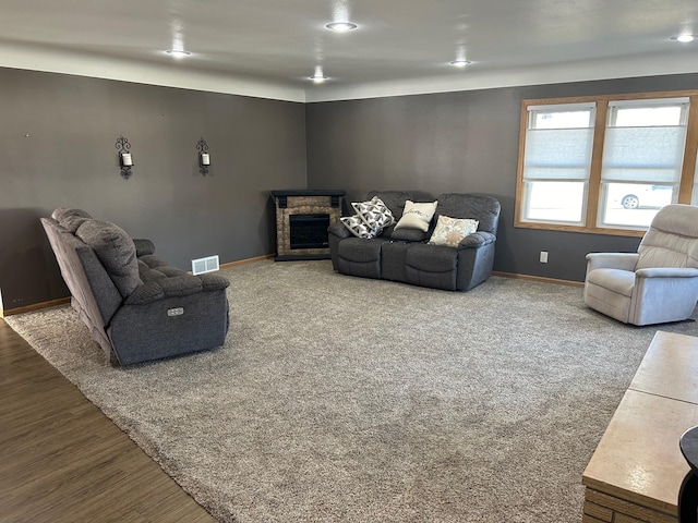 living room featuring a stone fireplace and carpet flooring