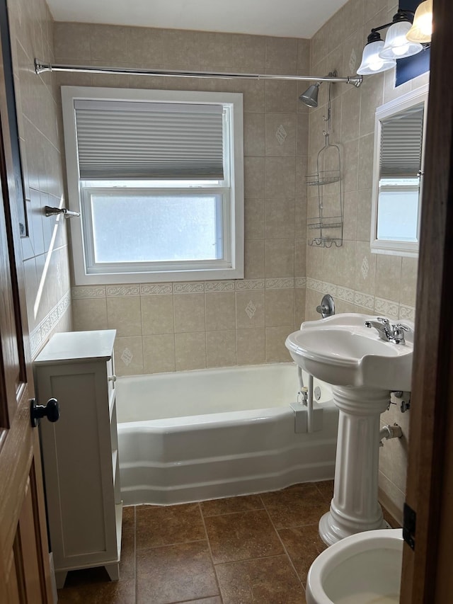 bathroom featuring tile walls, tile patterned flooring, tiled shower / bath, and toilet