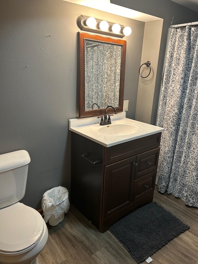 bathroom featuring toilet, vanity, and hardwood / wood-style floors