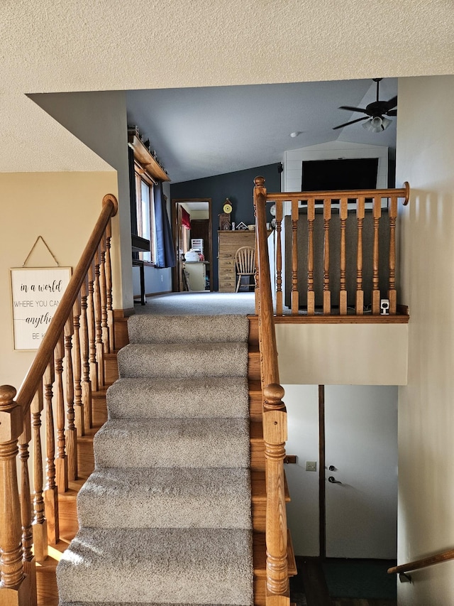 staircase with ceiling fan and vaulted ceiling