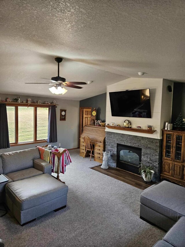 carpeted living room featuring ceiling fan, a fireplace, a textured ceiling, and lofted ceiling