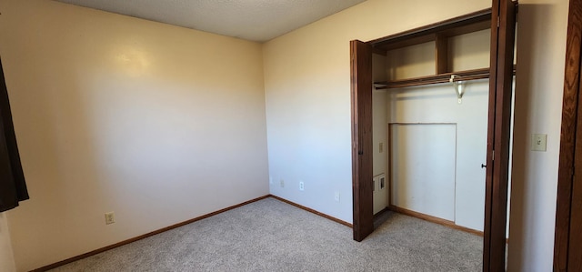 unfurnished bedroom featuring light colored carpet and a closet