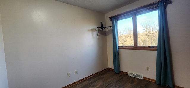 unfurnished room with a textured ceiling and dark hardwood / wood-style flooring