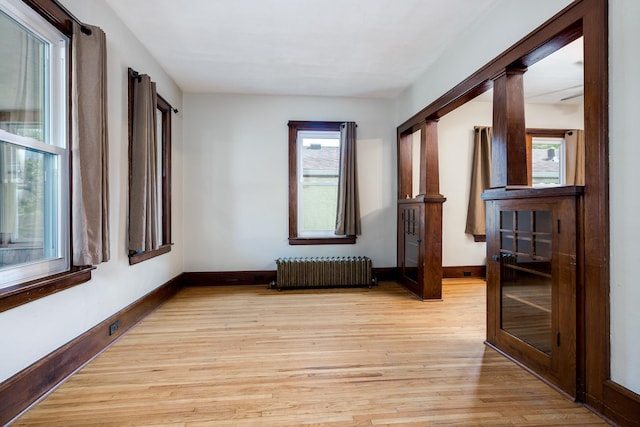 empty room with radiator heating unit and light hardwood / wood-style floors