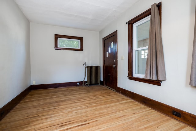 empty room featuring radiator heating unit and light hardwood / wood-style flooring