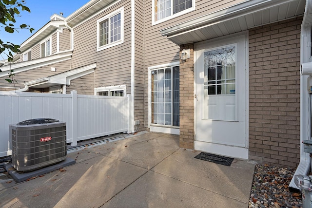 view of exterior entry with central AC unit and a patio