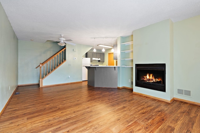 unfurnished living room with a textured ceiling, hardwood / wood-style flooring, and ceiling fan