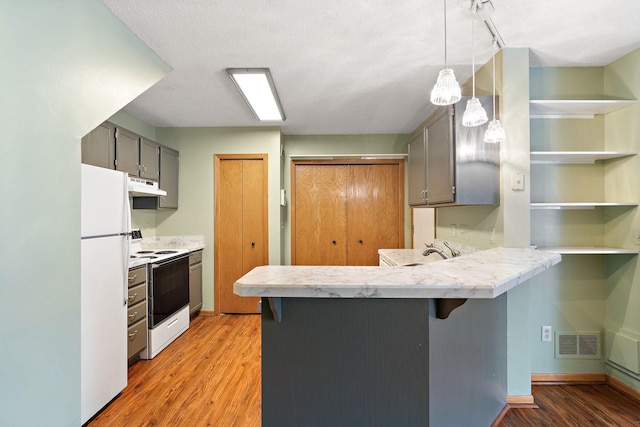 kitchen with a kitchen bar, kitchen peninsula, pendant lighting, and white appliances