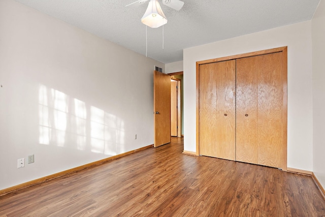 unfurnished bedroom with ceiling fan, wood-type flooring, a textured ceiling, and a closet